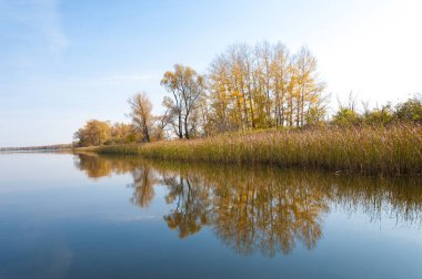 Sonbahar, sudaki ağaçların göldeki yansıması üzerine sessizdir.