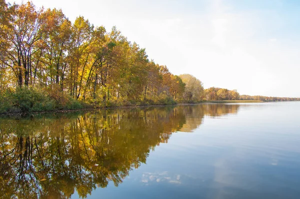 Sonbahar, sudaki ağaçların göldeki yansıması üzerine sessizdir.