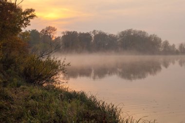  Manzara. Gölün üzerinde gün batımı, suya yansıyan düşen ağaçlar..