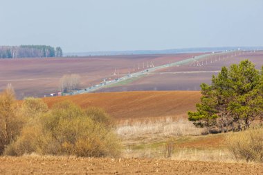 Bahar manzarası. Taze sürülmüş tarla. Tepe arazisi. Ağaçların zekası