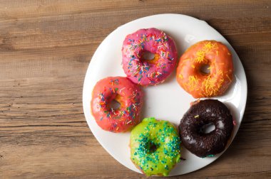 Çok renkli jöleli çörekler. Beyaz bir tabakta, tahta tahtalarda.