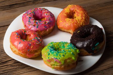 Çok renkli jöleli çörekler. Beyaz bir tabakta, tahta tahtalarda.