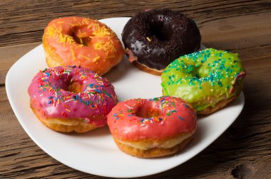 Çok renkli jöleli çörekler. Beyaz bir tabakta, tahta tahtalarda.