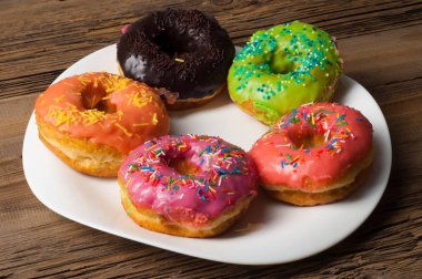 Çok renkli jöleli çörekler. Beyaz bir tabakta, tahta tahtalarda.