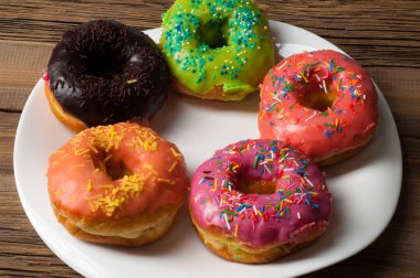 Çok renkli jöleli çörekler. Beyaz bir tabakta, tahta tahtalarda.