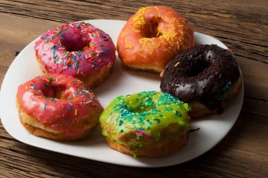 Çok renkli jöleli çörekler. Beyaz bir tabakta, tahta tahtalarda.