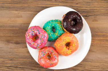 Çok renkli jöleli çörekler. Beyaz bir tabakta, tahta tahtalarda.