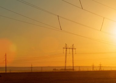Yüksek gerilim enerji nakil hattı. Enerji ayağı. Gün batımında,