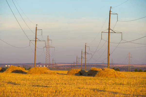 High-voltage power transmission line. Energy pillars. At sunset, — Stock Photo, Image