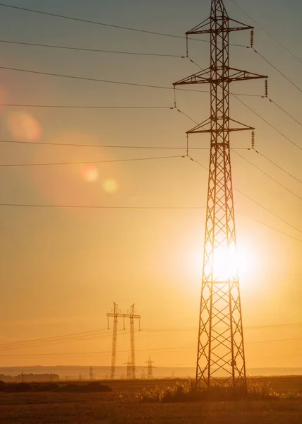 Linia elektroenergetyczna wysokiego napięcia. Filary energii. O zachodzie słońca, — Zdjęcie stockowe