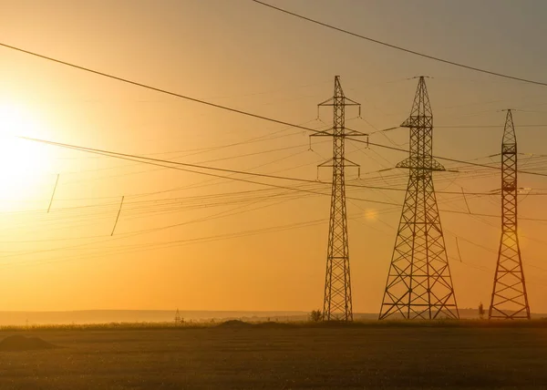 Linia elektroenergetyczna wysokiego napięcia. Filary energii. O zachodzie słońca, — Zdjęcie stockowe