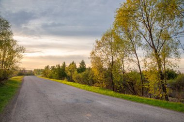 Bahar manzarası, gün doğumu. Bir köy yolu, kırsal bir arazi.