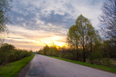 Bahar manzarası, gün doğumu. Bir köy yolu, kırsal bir arazi.