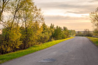 Bahar manzarası, gün doğumu. Bir köy yolu, kırsal bir arazi.