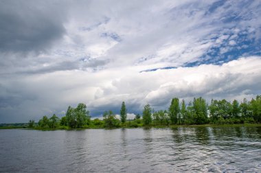 Yaz fotoğrafı, güçlü gök gürültülü bulutlar, mavi gökyüzü, karanlık keskin su, Kama Nehri boyunca turist yürüyüşü.