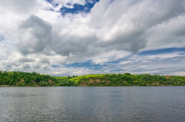 Yaz fotoğrafı, güçlü gök gürültülü bulutlar, mavi gökyüzü, karanlık keskin su, Kama Nehri boyunca turist yürüyüşü.