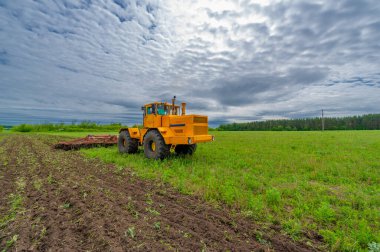 Bahar fotoğrafçılığı, ziraat makineleriyle manzara, bir traktör tarlayı sürüyor, tarlayı sürüyor, kuşlar ekilebilir arazinin üzerinde uçuyor.