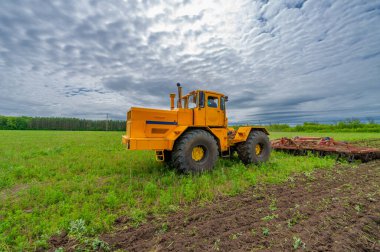 Bahar fotoğrafçılığı, ziraat makineleriyle manzara, bir traktör tarlayı sürüyor, tarlayı sürüyor, kuşlar ekilebilir arazinin üzerinde uçuyor.