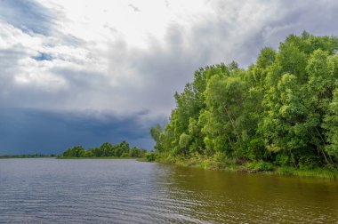Yaz fotoğrafı, güçlü gök gürültülü bulutlar, mavi gökyüzü, karanlık keskin su, Kama Nehri boyunca turist yürüyüşü.
