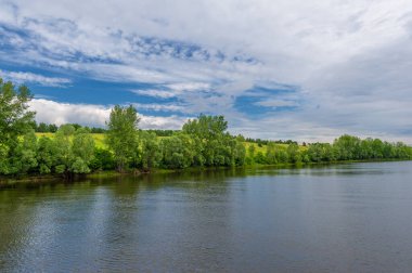 Yaz fotoğrafı, güçlü gök gürültülü bulutlar, mavi gökyüzü, karanlık keskin su, Kama Nehri boyunca turist yürüyüşü.