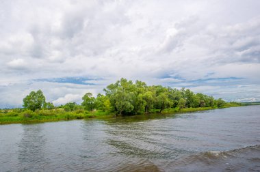 Yaz fotoğrafı, güçlü gök gürültülü bulutlar, mavi gökyüzü, karanlık keskin su, Kama Nehri boyunca turist yürüyüşü.