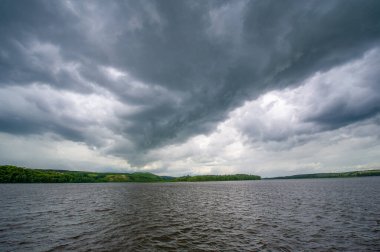 Yaz fotoğrafı, güçlü gök gürültülü bulutlar, mavi gökyüzü, karanlık keskin su, Kama Nehri boyunca turist yürüyüşü.