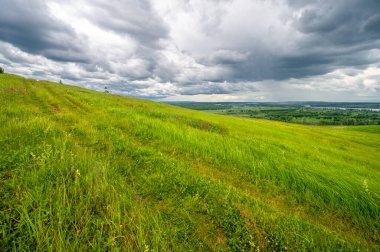 Yaz fotoğrafçılığı, yeşil çimenler, güçlü gök gürültülü bulutlar, mavi gökyüzü, Kama Nehri boyunca turist yürüyüşü