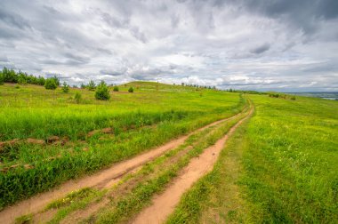 Yaz fotoğrafçılığı, yeşil çimenler, güçlü gök gürültülü bulutlar, mavi gökyüzü, Kama Nehri boyunca turist yürüyüşü