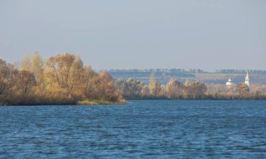 Sonbahar manzarası, koyu mavi su, son sıcak günler, nehir, ağaçlar, rüzgarlı hava, sarı-kırmızı sonbahar yaprakları.