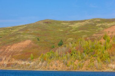 Sonbahar manzarası, koyu mavi su, son sıcak günler, nehir, ağaçlar, rüzgarlı hava, sarı-kırmızı sonbahar yaprakları.