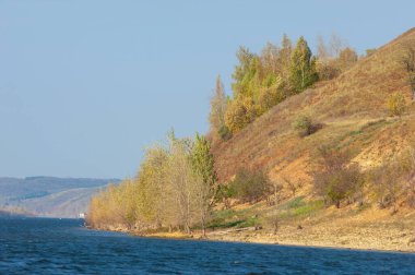 Sonbahar manzarası, koyu mavi su, son sıcak günler, nehir, ağaçlar, rüzgarlı hava, sarı-kırmızı sonbahar yaprakları.