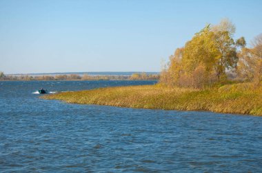 Sonbahar manzarası, koyu mavi su, son sıcak günler, nehir, ağaçlar, rüzgarlı hava, sarı-kırmızı sonbahar yaprakları.