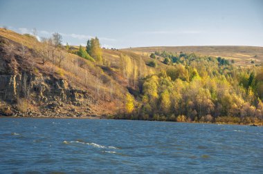 Sonbahar manzarası, koyu mavi su, son sıcak günler, nehir, ağaçlar, rüzgarlı hava, sarı-kırmızı sonbahar yaprakları.