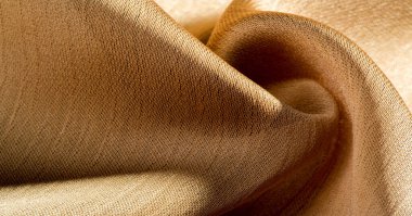 Arka plan, desen, doku, bej altın ipek kumaş Pürüzsüz mat bir kaplamaya sahiptir ve hafif bükümlü bir iplik sayesinde dayanıklıdır. Tasarımdan projelerinize kadar her şey için bu lüks kumaşı kullanın