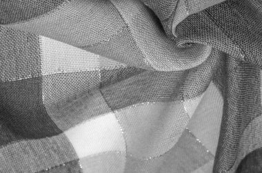 Doku, arkaplan, ipek atkı siyah beyaz, metal şeritli. Eşarp, soyut İskoç motifleriyle pastel renklerle hassas bir yama deseniyle süslenmiş. kontrol edilen kumaş