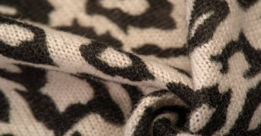 Doku, arkaplan, desen, kadın yün şalı, siyah ve bej, Afrika motifleri, yün ve modülden yapılmış, kenarları kıvrımlı bir yılan şeklinde..