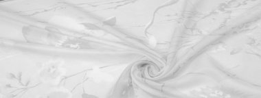 Doku, arka plan, gri çiçekli beyaz ipek süs. Kumaşın bir Jacquard dokuması var. Bu kumaş sayesinde yumuşak bir şekilde parıldayan saten bölümler elde etti.