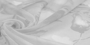 Doku, arka plan, gri çiçekli beyaz ipek süs. Kumaşın bir Jacquard dokuması var. Bu kumaş sayesinde yumuşak bir şekilde parıldayan saten bölümler elde etti.