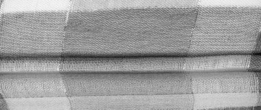 Doku, arkaplan, ipek atkı siyah beyaz, metal şeritli. Eşarp, soyut İskoç motifleriyle pastel renklerle hassas bir yama deseniyle süslenmiş. kontrol edilen kumaş