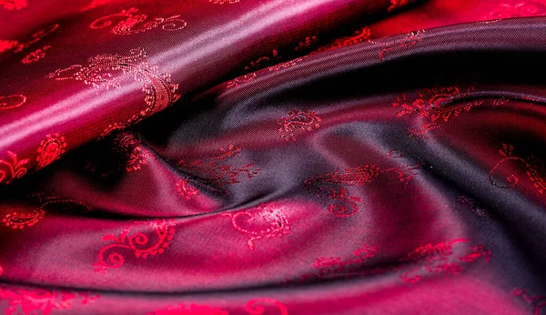 Texture, fabric, red silk with paisley pattern. This beautiful printed silk Charmeuse has a bold paisley pattern. In the patriotic appearance there are colors red, The fabric has a slippery hand