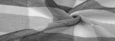 Doku, arkaplan, ipek atkı siyah beyaz, metal şeritli. Eşarp, soyut İskoç motifleriyle pastel renklerle hassas bir yama deseniyle süslenmiş. kontrol edilen kumaş