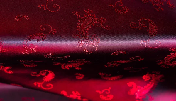 Texture, fabric, red silk with paisley pattern. This beautiful printed silk Charmeuse has a bold paisley pattern. In the patriotic appearance there are colors red, The fabric has a slippery hand