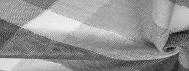 Doku, arkaplan, ipek atkı siyah beyaz, metal şeritli. Eşarp, soyut İskoç motifleriyle pastel renklerle hassas bir yama deseniyle süslenmiş. kontrol edilen kumaş