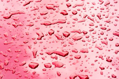 Yaz yağmuru, araba boyasının üzerine bir damla su. Sıvının küçük yuvarlak ya da armut şeklinde bir kısmı bir yüzeye tutunur ya da düşer..