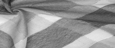 Doku, arkaplan, ipek atkı siyah beyaz, metal şeritli. Eşarp, soyut İskoç motifleriyle pastel renklerle hassas bir yama deseniyle süslenmiş. kontrol edilen kumaş