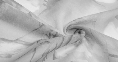 Doku, arka plan, gri çiçekli beyaz ipek süs. Kumaşın bir Jacquard dokuması var. Bu kumaş sayesinde yumuşak bir şekilde parıldayan saten bölümler elde etti.