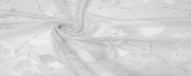 Doku, arka plan, gri çiçekli beyaz ipek süs. Kumaşın bir Jacquard dokuması var. Bu kumaş sayesinde yumuşak bir şekilde parıldayan saten bölümler elde etti.