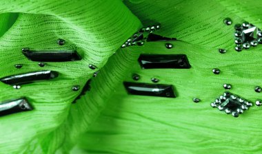 Arkaplan tasarımı dokusu, ipek desen, yeşil kumaş ve dekoratif işlemeli taşlar.