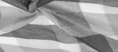 Doku, arkaplan, ipek atkı siyah beyaz, metal şeritli. Eşarp, soyut İskoç motifleriyle pastel renklerle hassas bir yama deseniyle süslenmiş. kontrol edilen kumaş