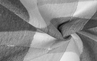 Doku, arkaplan, ipek atkı siyah beyaz, metal şeritli. Eşarp, soyut İskoç motifleriyle pastel renklerle hassas bir yama deseniyle süslenmiş. kontrol edilen kumaş